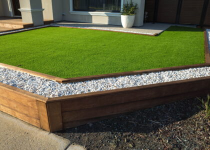 Artificial turf with wooden frame around it in backyard.