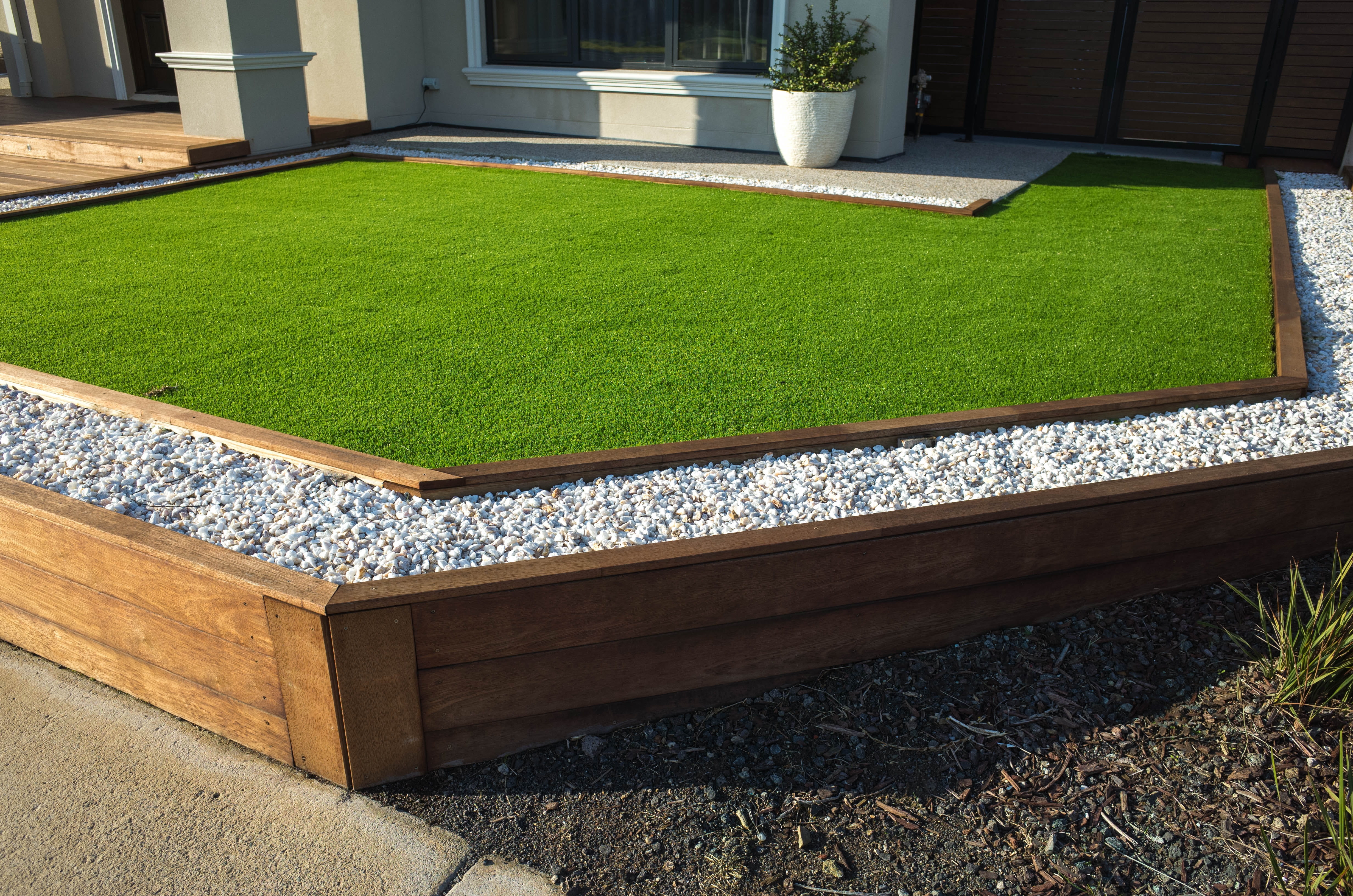 Artificial turf with wooden frame around it in backyard.
